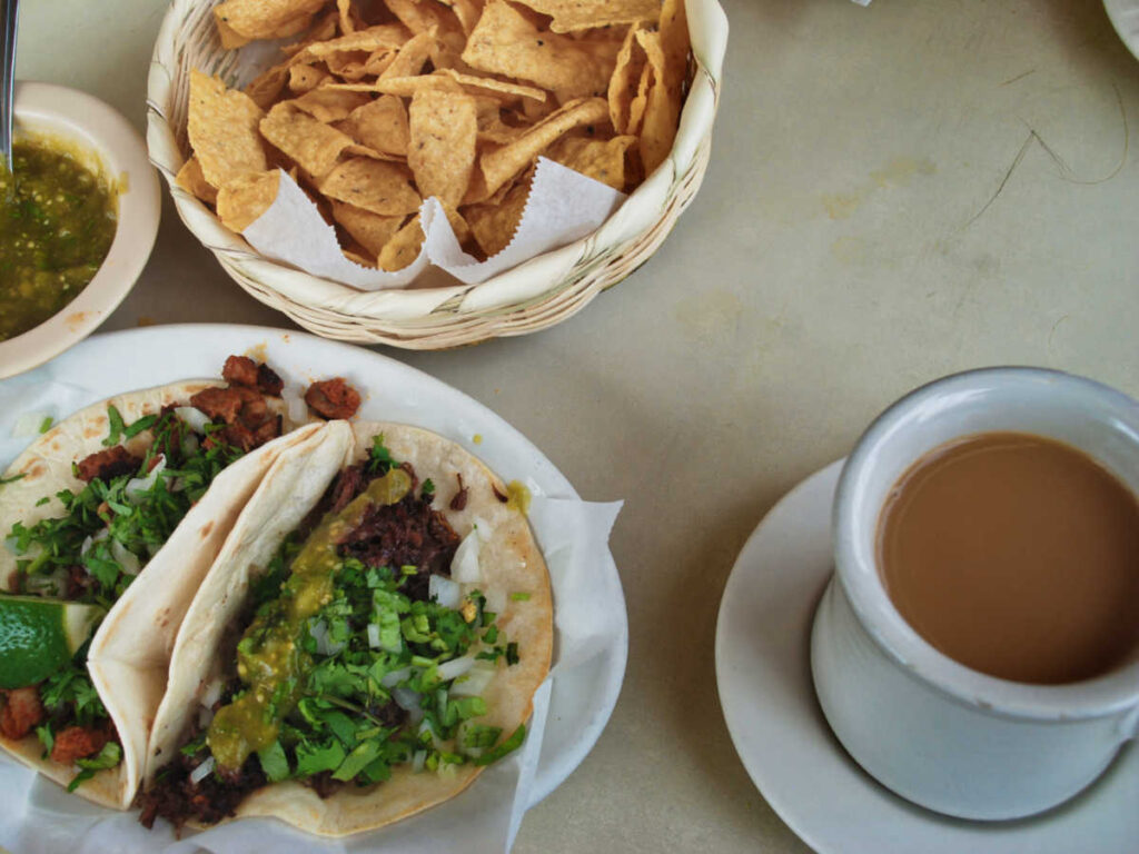 A variety of Mexican foods with a cup of coffee on the table