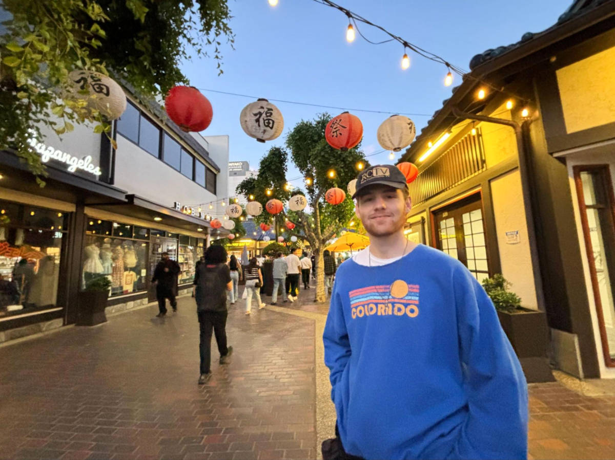 Betty's boyfriend smiling for a photo by the lanterns in Little Tokyo