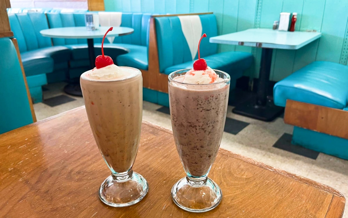 Two glasses of milkshakes topped with cherries