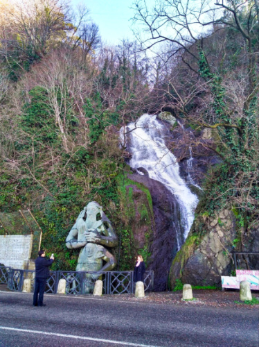 A waterfall and a monument on the side of the road in Gonio