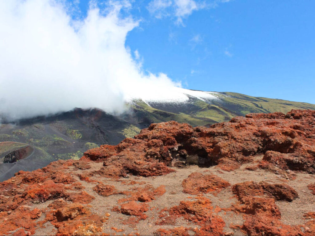 View of the bright red lava rocks and the Mount Etna in the background