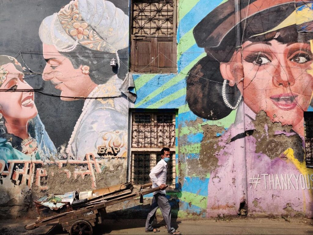 A man walks past a large Bollywood-inspired murals at Bandra’s Chapel Road