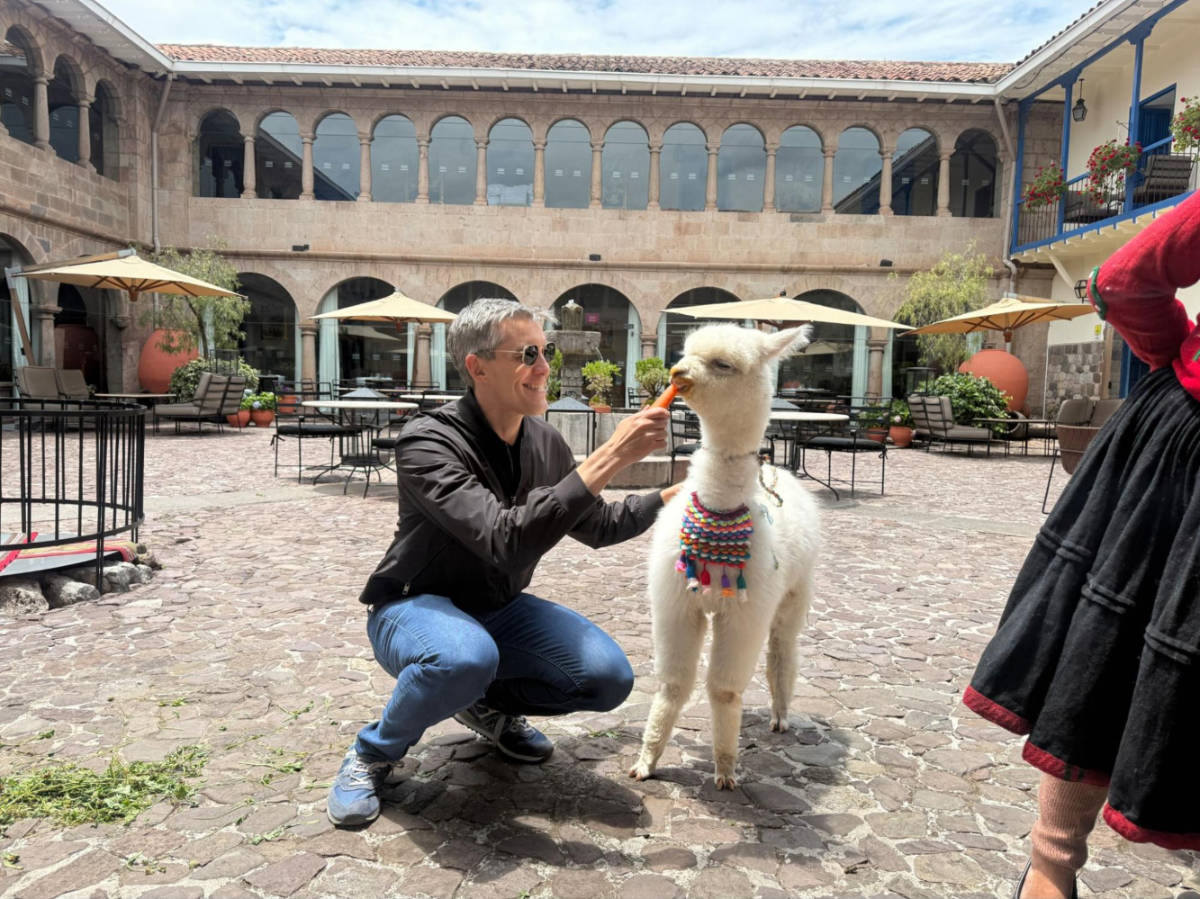 The author Nate Hake, feeding a carrot to an alpaca in Palacio del Inka