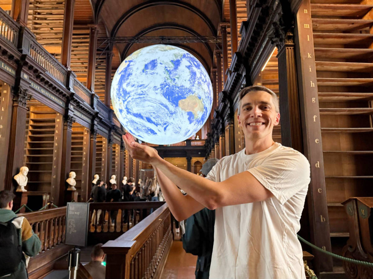 Nate Hake posing for a photo with the globe at the Old Library’s Long Room