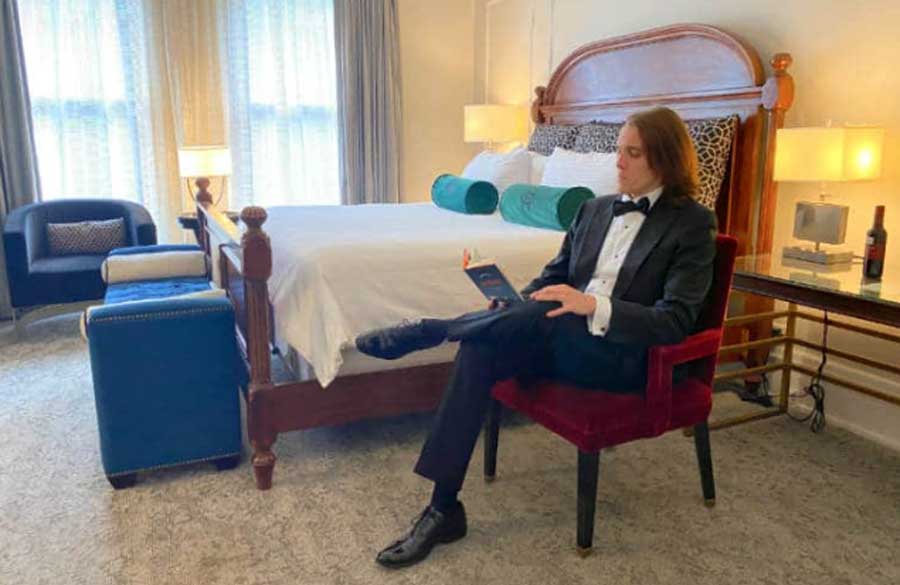 Nate reading a book while sitting on her room at the Oxford Hotel