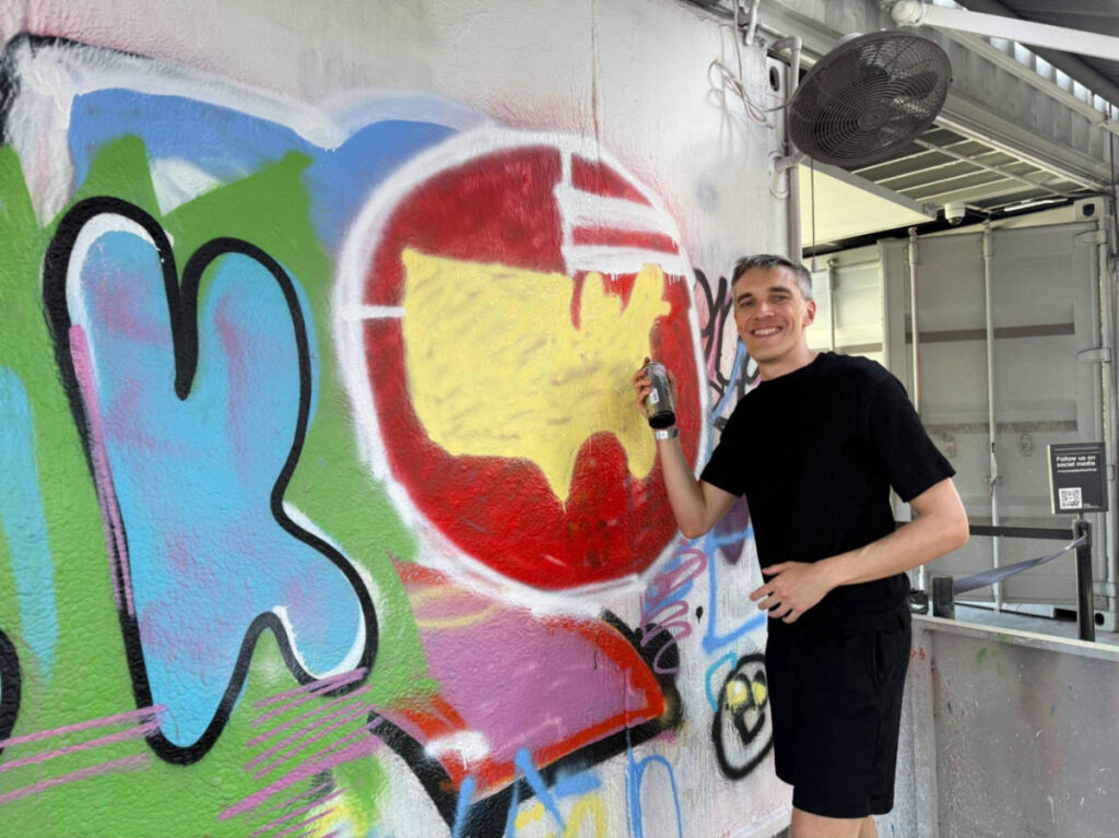 Travel Lemming founder, Nate Hake spray painting on a cemented wall