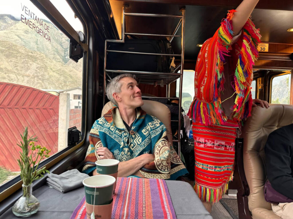 Travel Lemming Founder Nate Hake, smiling while watching the performer on the Inca Rail Prime train to Ollantaytambo