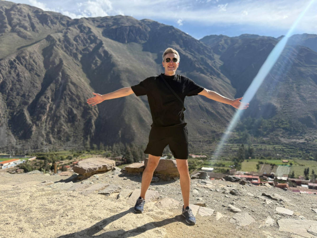 Travel Lemming founder Nate Hake, posing for a photo at the peak of the Ollantaytambo Inca ruins on a windy day
