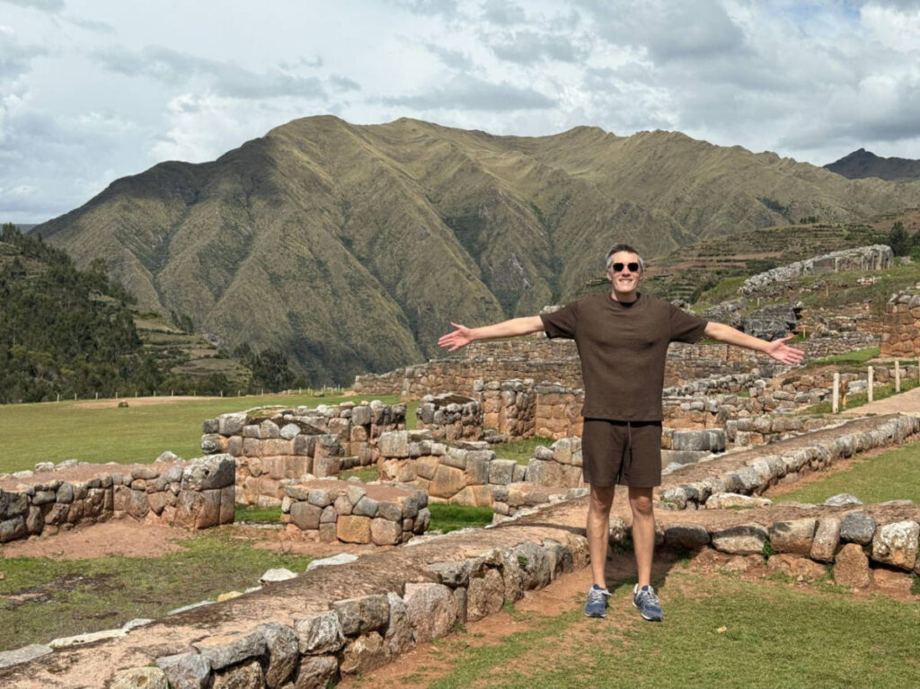 Travel Lemming founder Nate Hake, posing for a photo with an overlooking view of the ruins of Chinchero