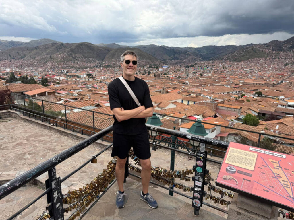 Travel Lemming Founder Nate Hake, posing for a photo with an overlooking view of the San Blas Mirador in Cusco