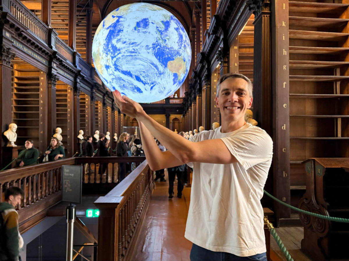 Travel Lemming founder Nate taking a photo with the globe at the Trinity College Long Room