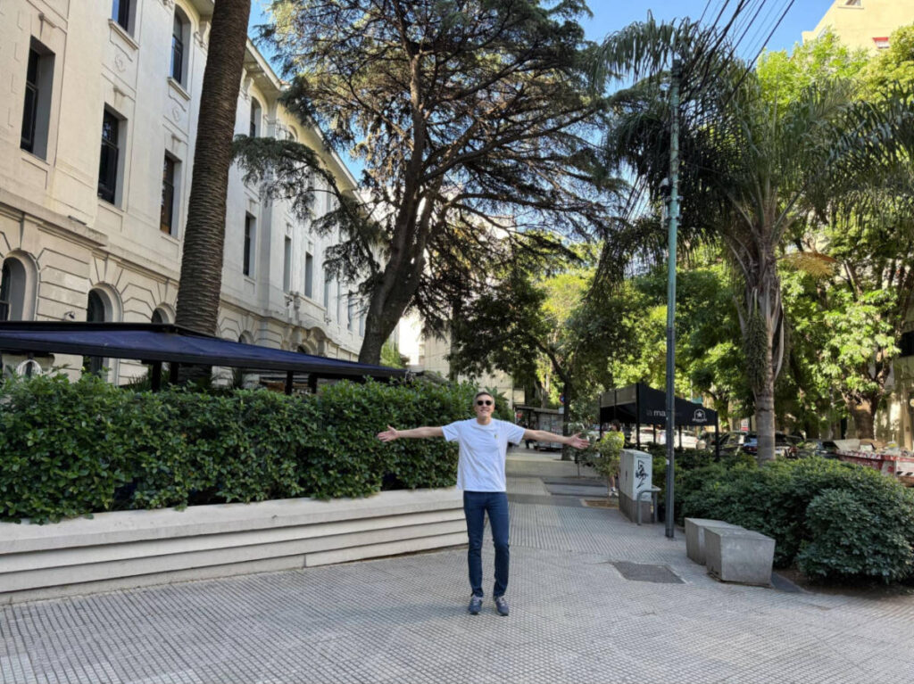 Travel Lemming founder, Nate Hake, posing for a photo near the entrance to Uptown bar surrounded by greenery