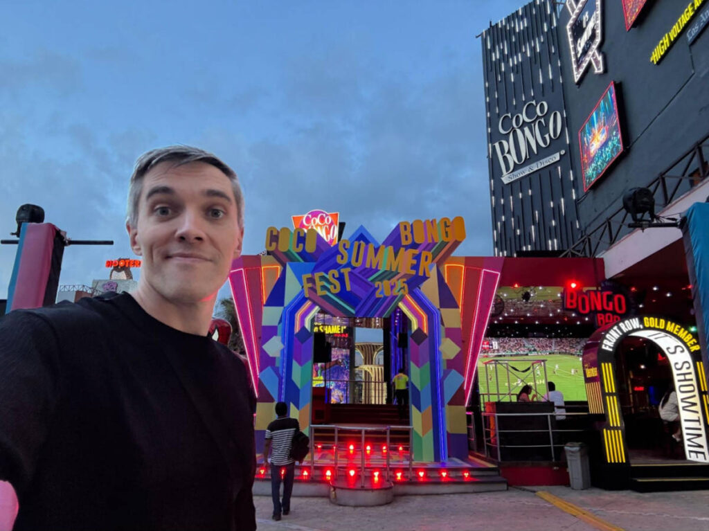 Travel Lemming founder Nate Hake standing in front of Coco Bongo illuminated with colorful lights