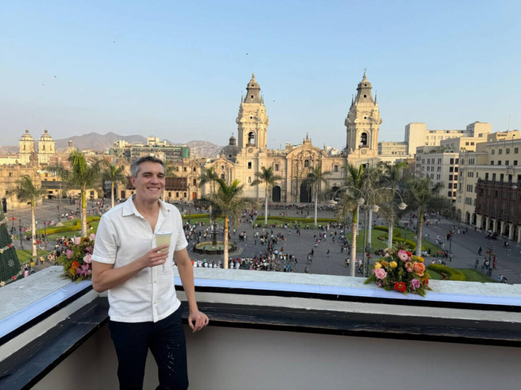 Travel Lemming Founder Nate Hake, holding a glass of Pisco Sour on the Terraza Lima Club