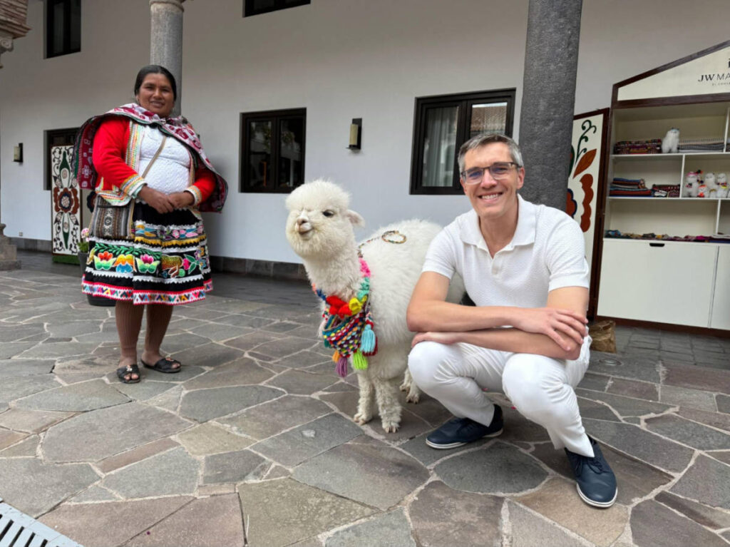 Travel Lemming founder Nate Hake, smiling for a photo with Panchita, the resident alpaca at JW Marriott El Convento Cusco