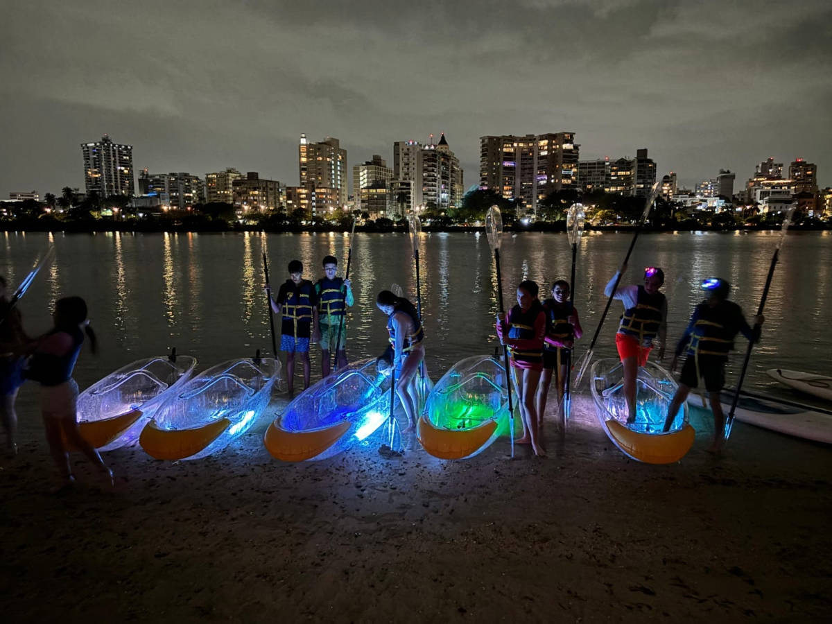 People getting ready with their illuminated kayak in Condado Lagoon at night
