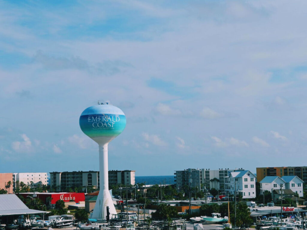 A water tower with the words “Emerald Coast” rises above the buildings of Okaloosa Island