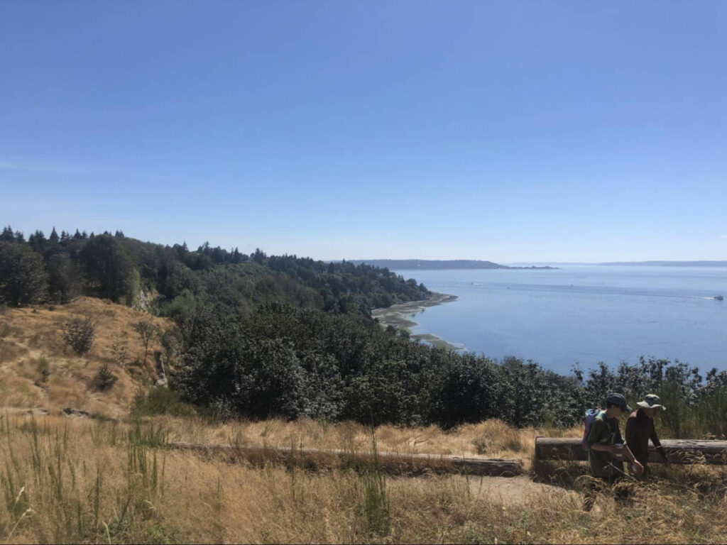 People hiking at the Bluffs with an overlooking view of the Discovery Park