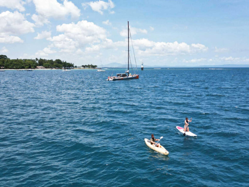 Aerial view of the people paddleboarding and kayaking with the boat in the background