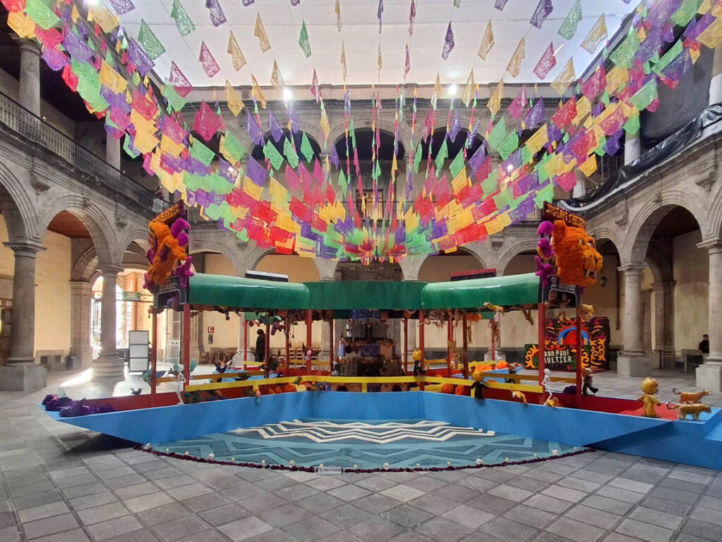 The colorful Papeles Picados hanging over the Jean Paul Gaultier ofrenda