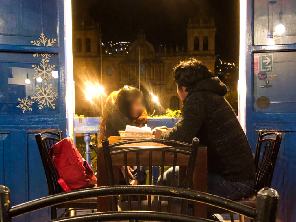 People dining near the window overlooking the Plaza de Armas