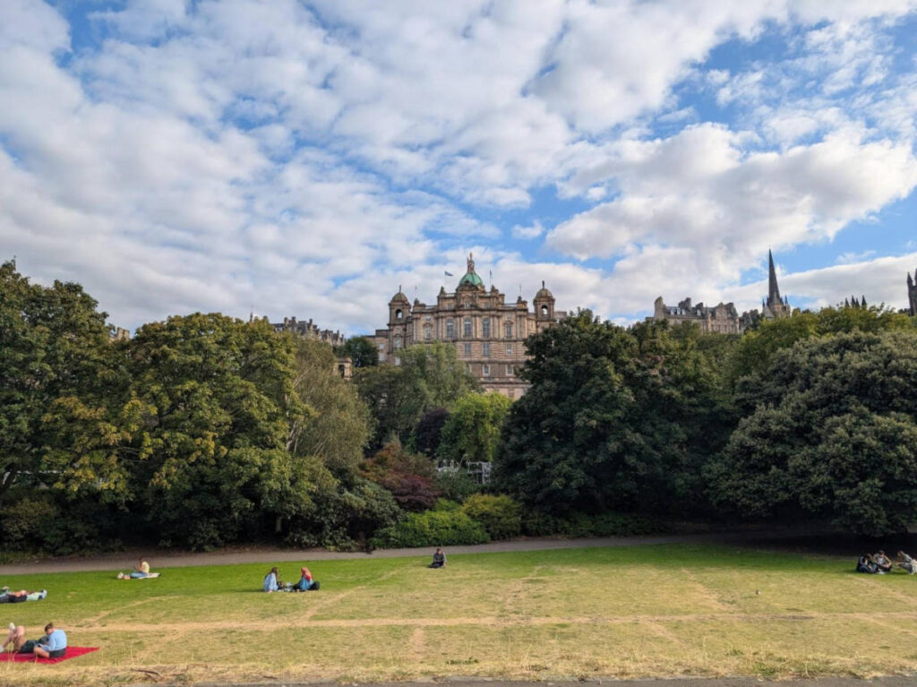 People sunbathing on a sunny day with the Edinburgh Castle view