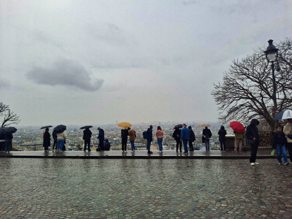 View of the people enjoying the overlooking view of the city from Montmartre on a rainy day