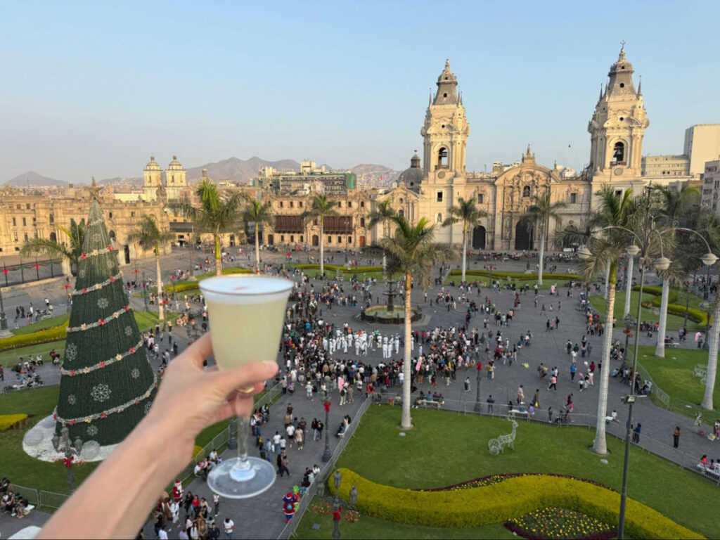 Holding a Pisco Sour at Terraza Lima Club with overlooking view of Plaza Mayor