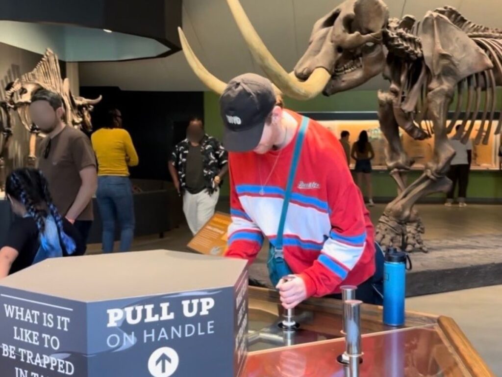 Michael trying the tar pit resistance interactive exhibit at the La Brea Tar Pits museum
