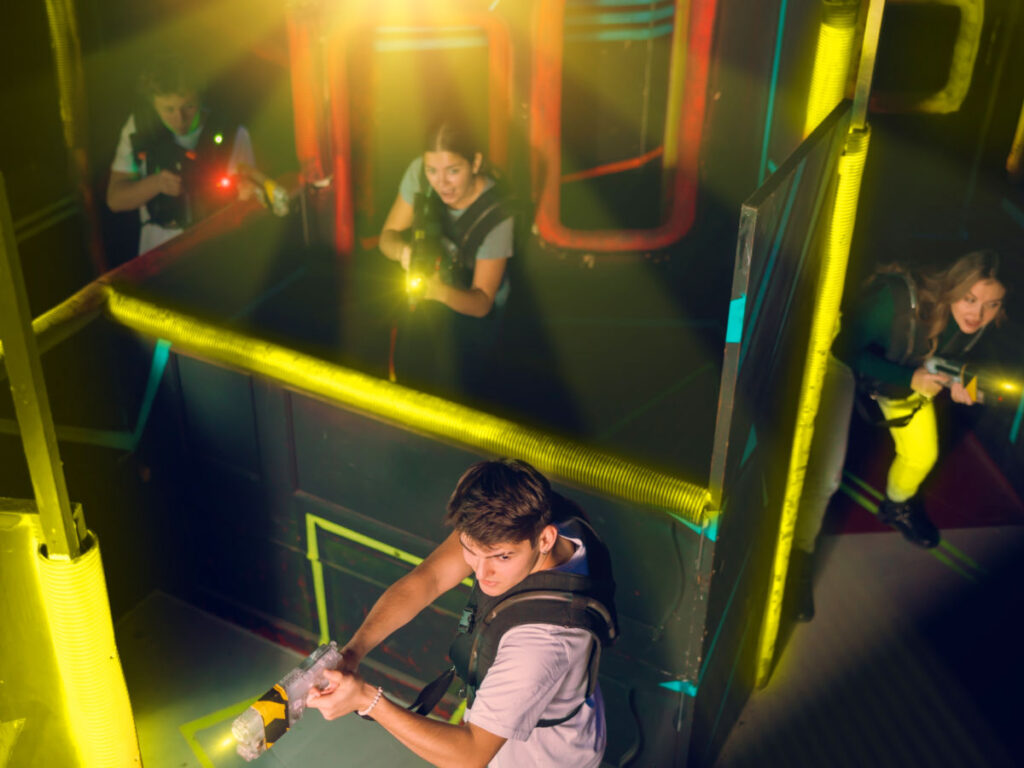 Team of young people play laser tag in a labyrinth