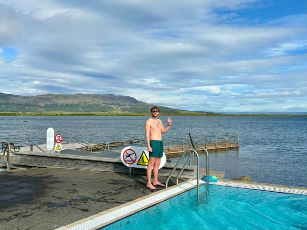 A man posing for a photo near the pool and the lake at Laugarvatn Fontana