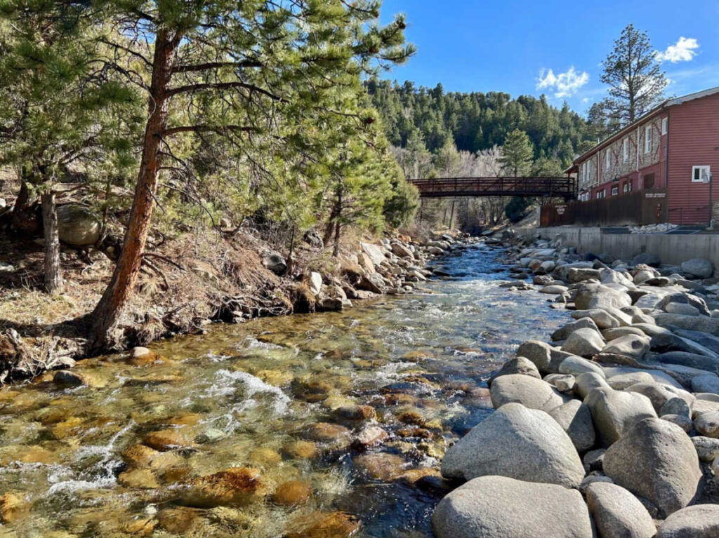 A creek winding through lined with rocks and trees at Mount Princeton Hot Springs Resort