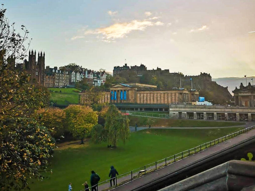 People wandering around Princes Street Garden and the National Gallery of Scotland at Sunset