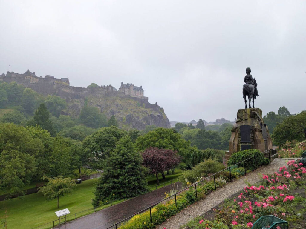 A statue at the Princes Street Gardens on a rainy day with the Edinburgh Castle view from a distance
