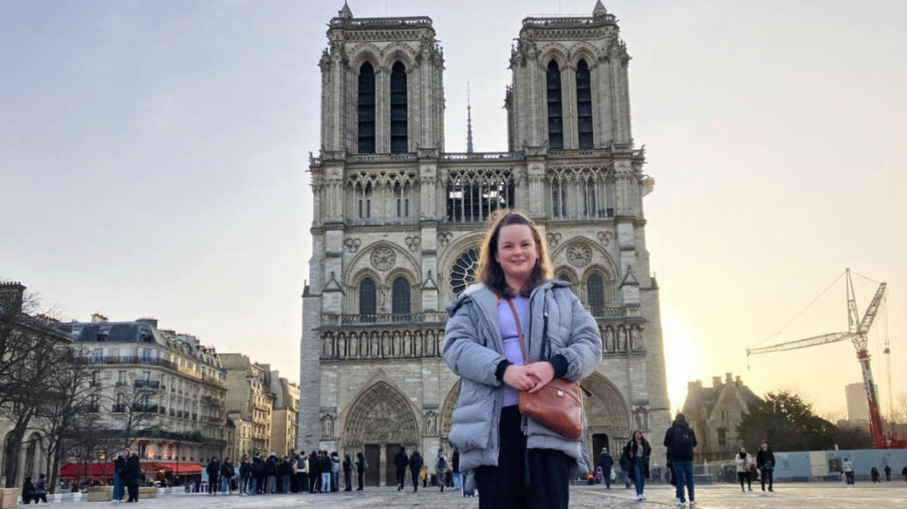 The author Rachel Kapelke-Dale standing in front of Notre Dame Cathedral