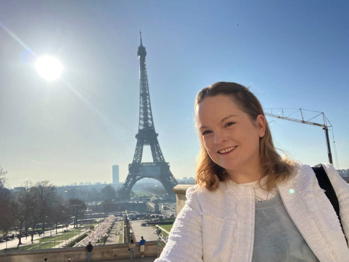 The author, Rachel Kapelke-Dale, smiling for a photo with the view of the Eiffel Tower at Trocadero