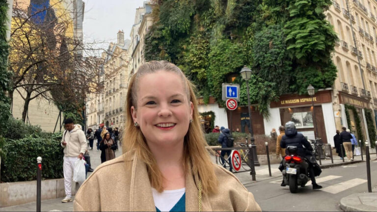 The author Rachel Kapelke-Dale, smiling for a photo at the border of the Mail and Bonne-Nouvelle quarters