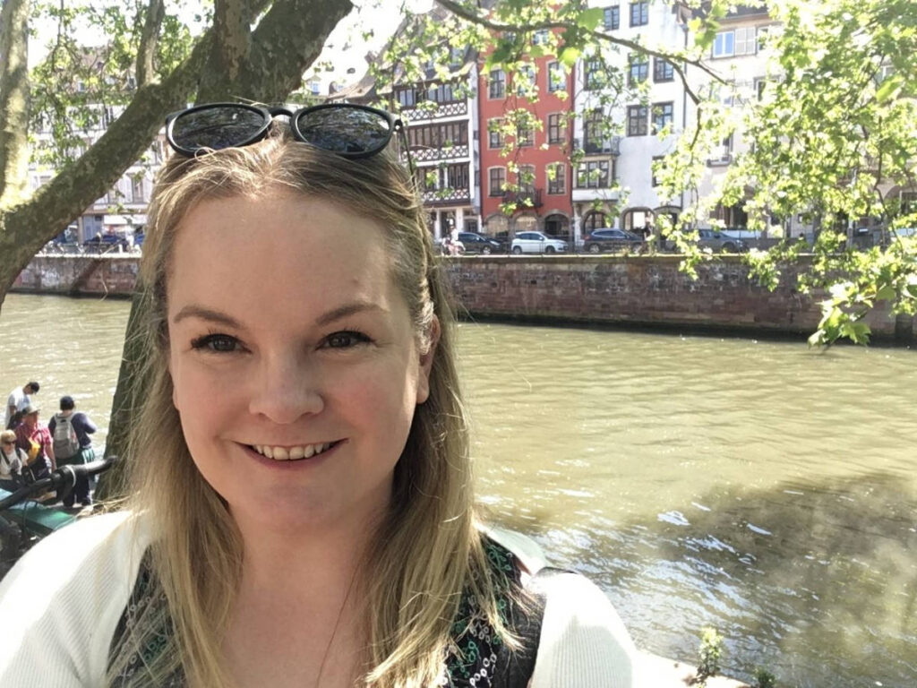 The author Rachel Kapelke-Dale, smiling for a photo near the Boure-side canal