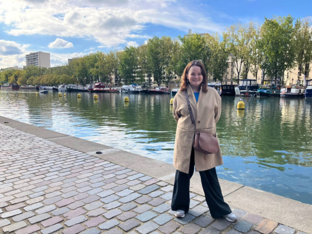 The author Rachel Kapelke-Dale standing by the Canal de l’Ourcq surrounded by lush trees