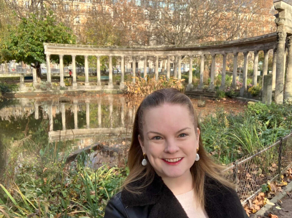 The author Rachel Kapelke-Dale, smiling for a photo at the Parc Monceau