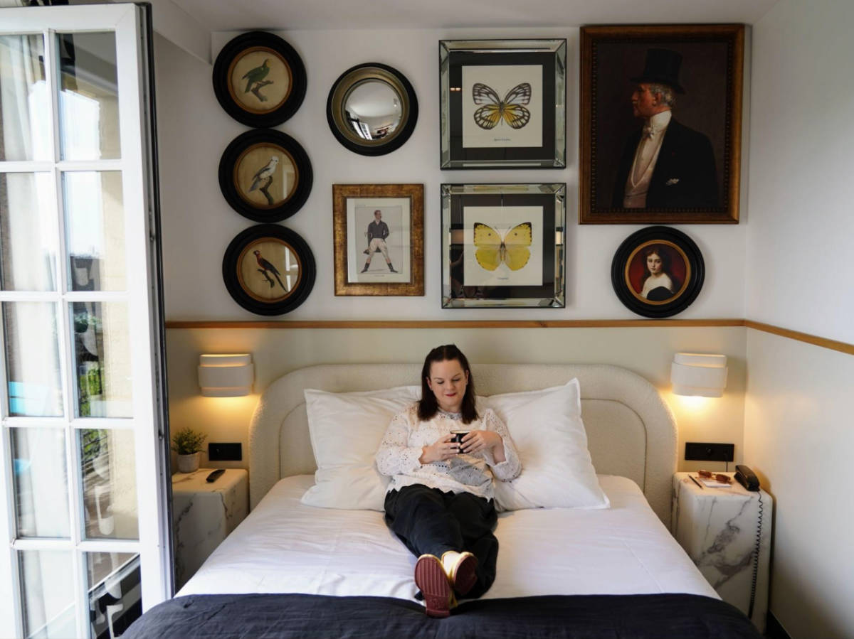 Travel Lemming writer Rachel on the hotel bed with a gallery wall in the background