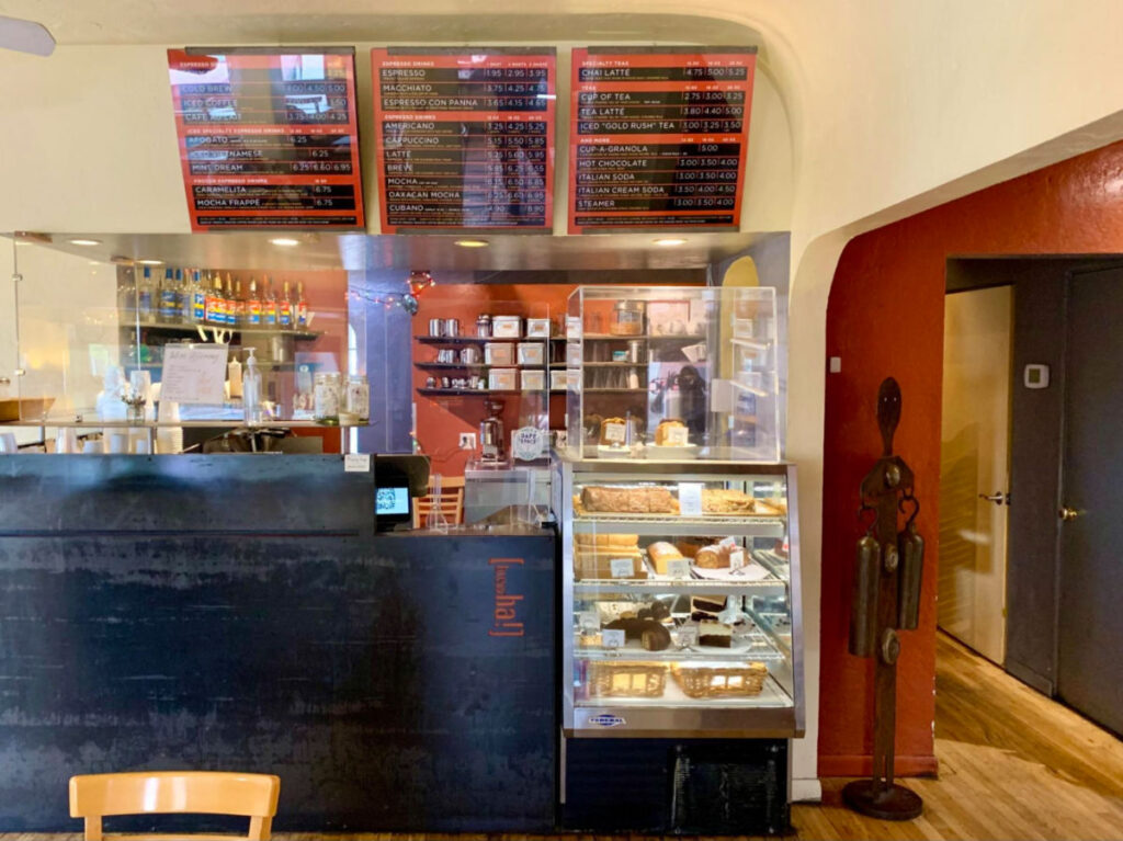 Inside Raging Sage Coffee Roasters showing the menu and cake displays