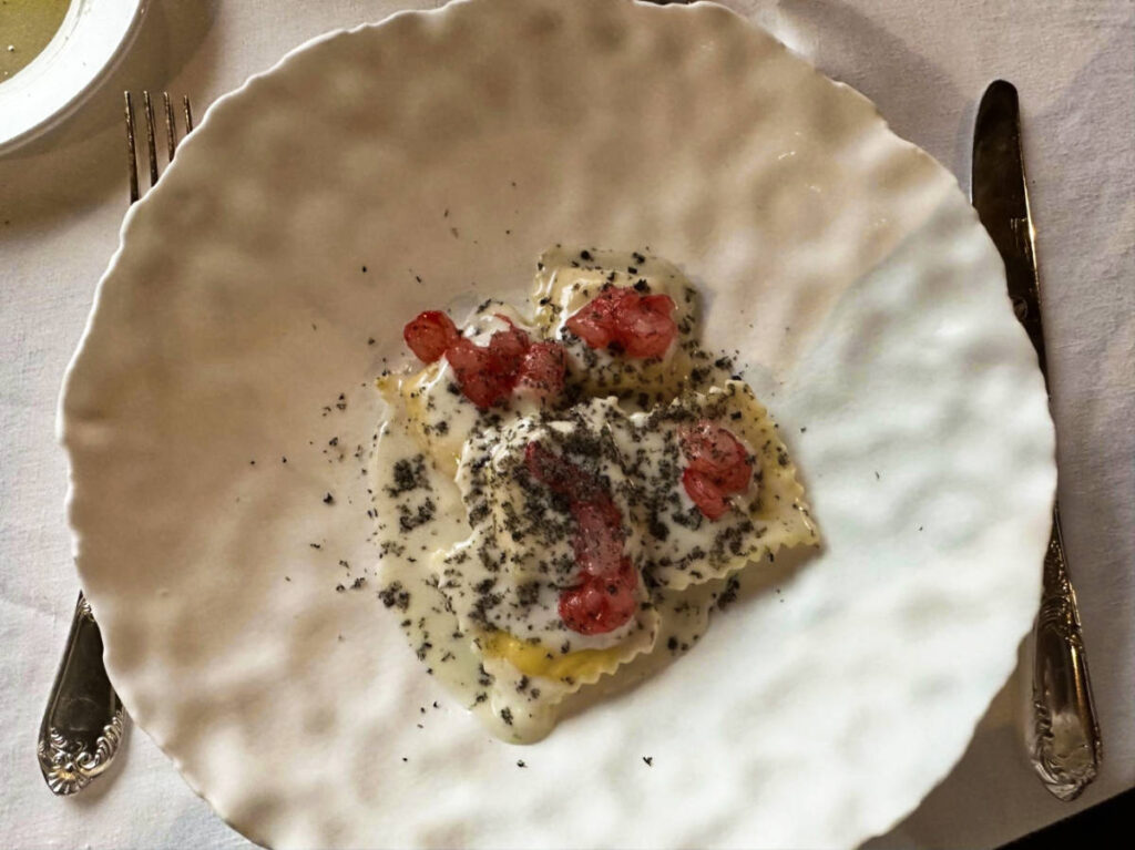 A plate with ravioli topped with fresh red prawns
