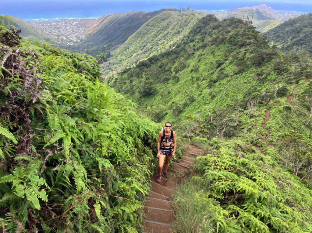 The author Rebecca Parsons on the stairs surrounded by greenery on a hike in Oahu