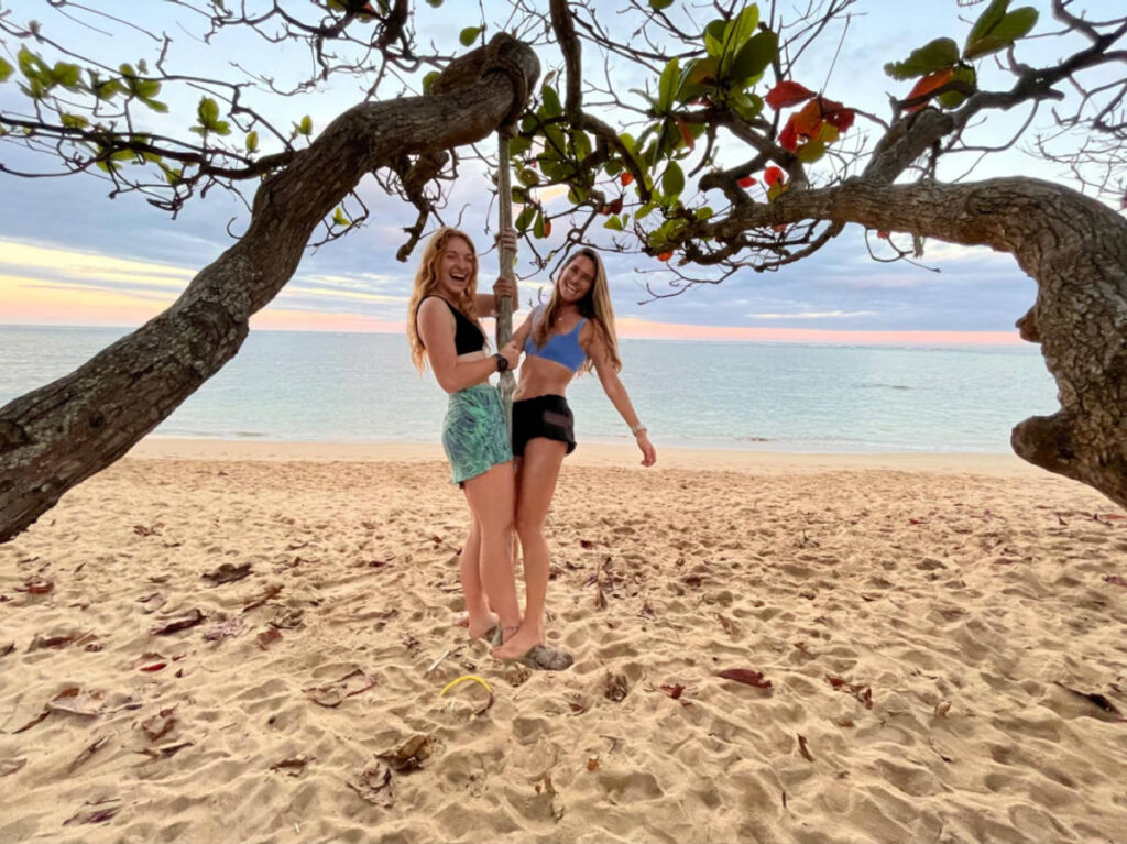 The author Rebecca Parsons and her friend tree swinging at the beachfront