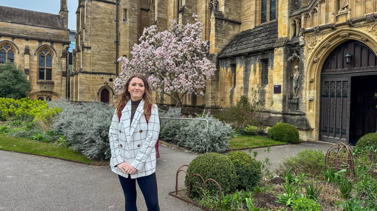 The author Rebecca Rayner, posing for a photo in front of the Historic Oxford Colleges