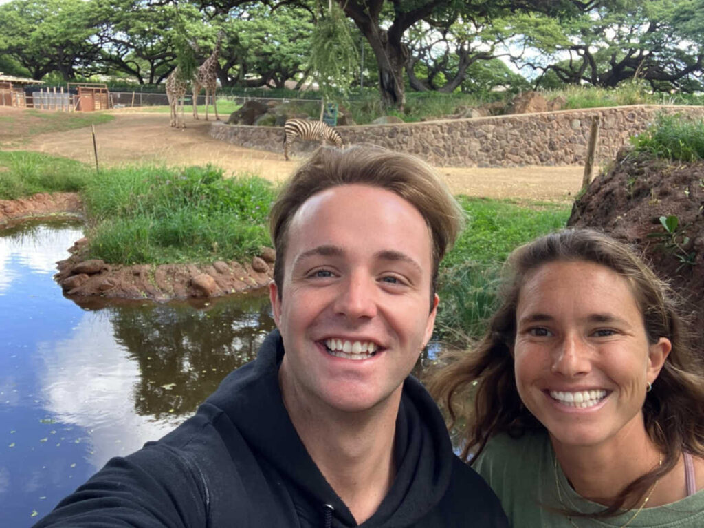 The author Rebecca Parsons with a man posing for a photo with the giraffes in the background