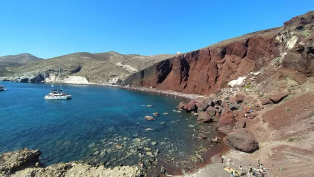 View of the red cliffs and the boat sailing on the Red Beach
