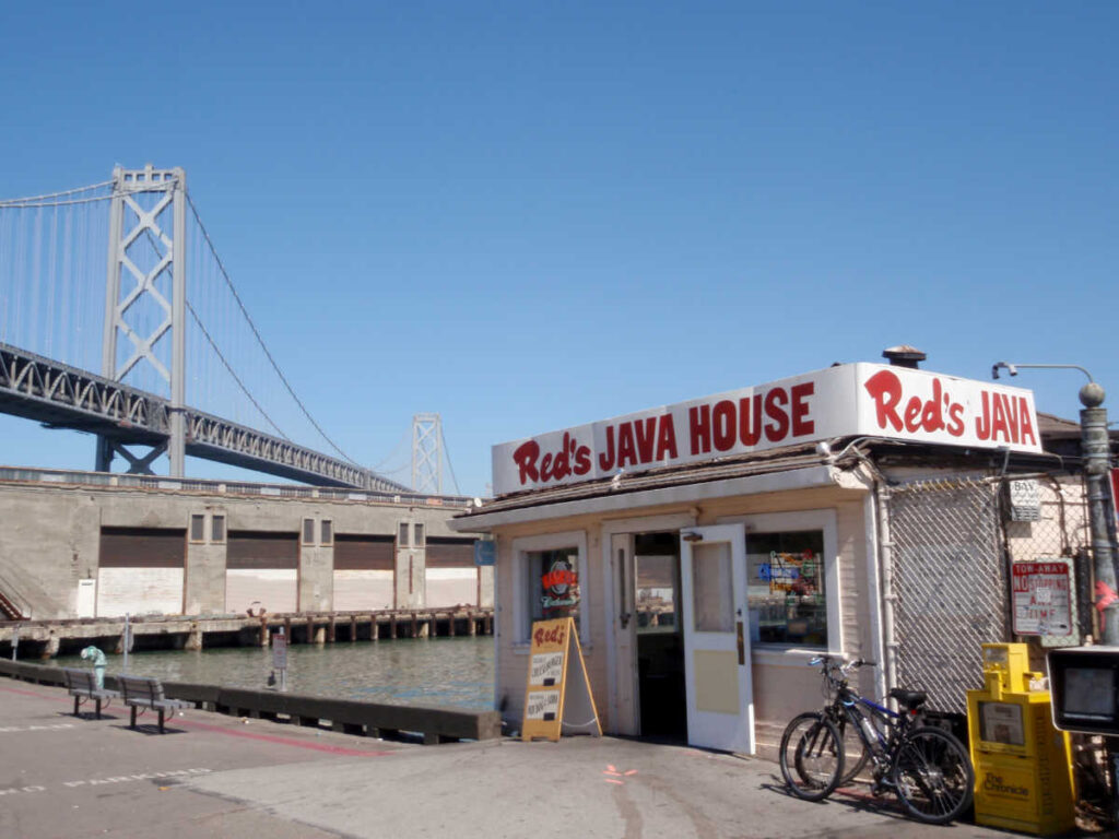 Exterior view of the Red’s Java House and the Bay Bridge in the background