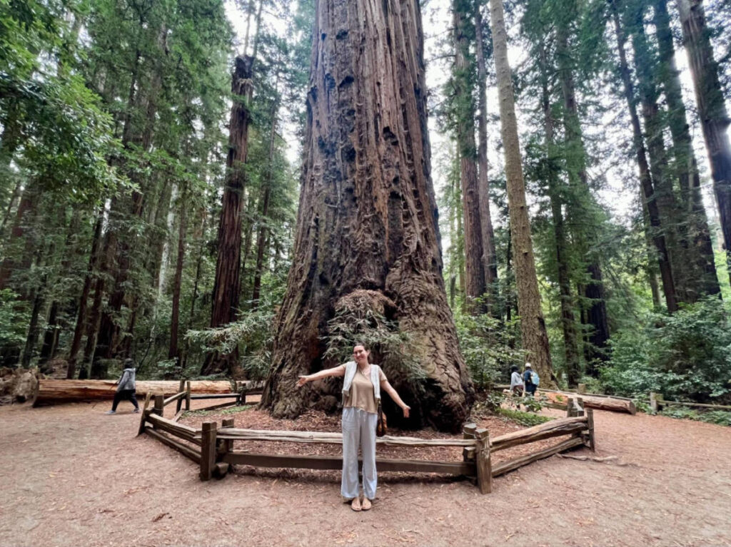 Author Laura posing for a photo in front of a redwood tree in Henry Cowell Redwoods State Park